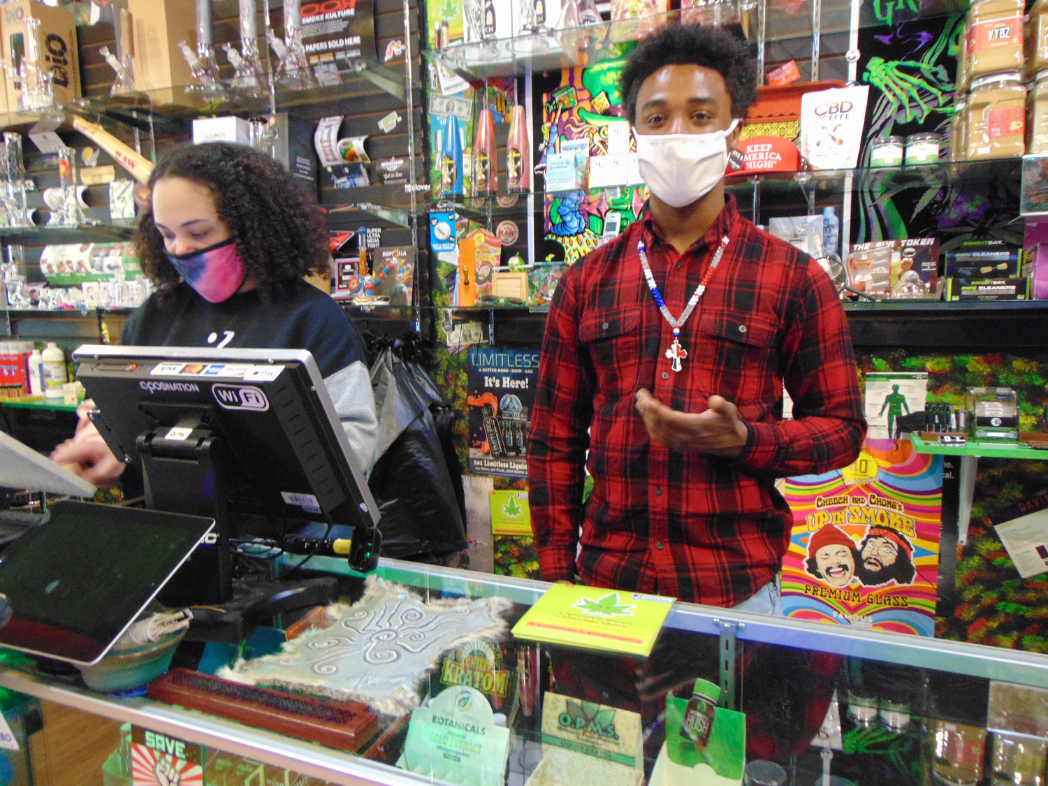 Two of our friendly staff members working behind the counter at the FXBG store with various products on shelves.
